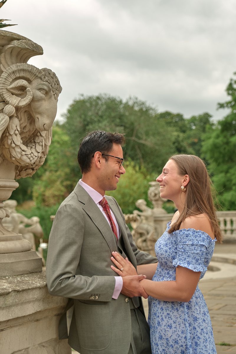 Victor and Lucy face to face beside a carved stone urn