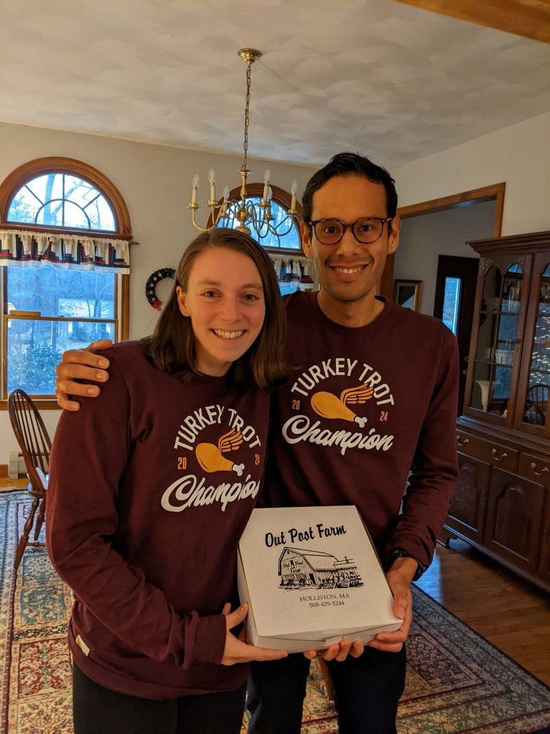 Lucy and Victor in matching race shirts, holding a sign