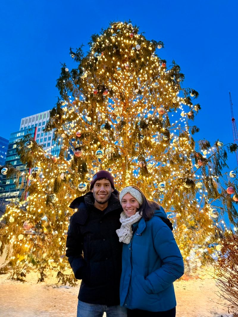Lucy and Victor in front of a giant lit Christmas tree
